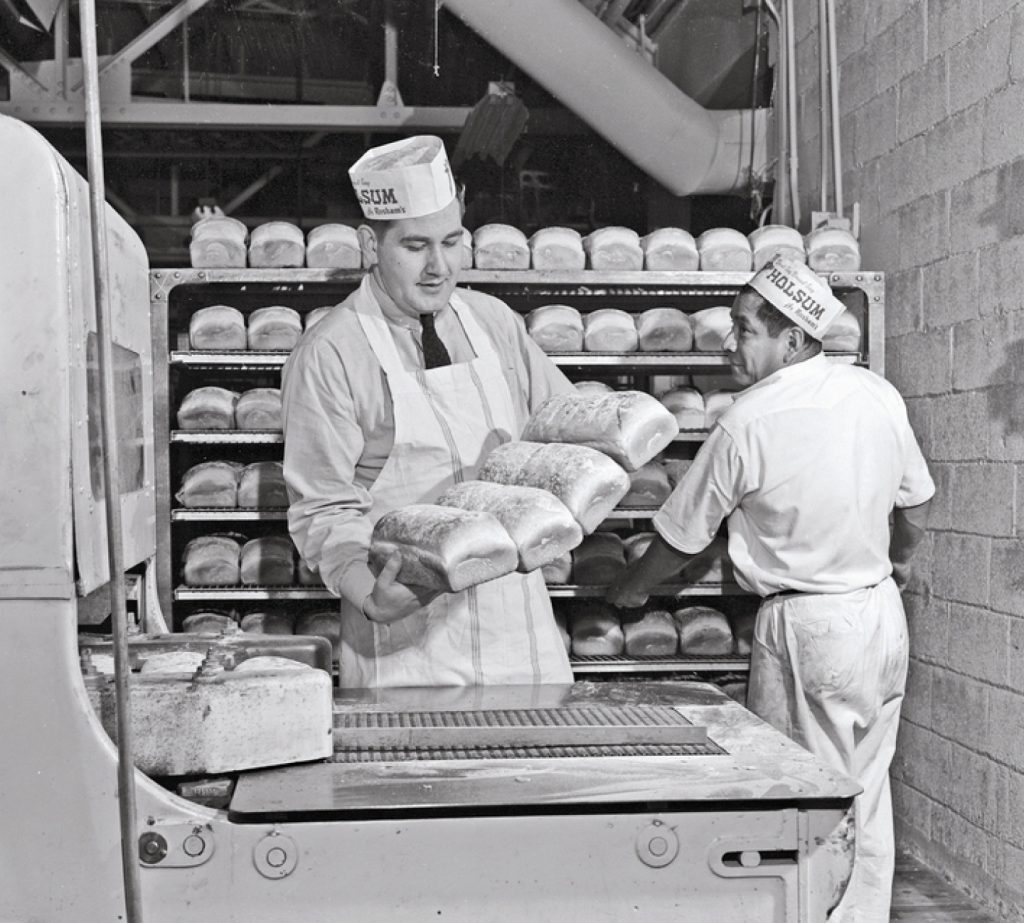 Historical photo of a baker holing loaves of bread