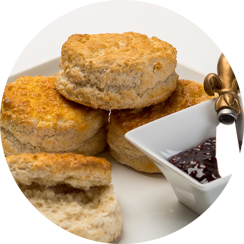 Four scones on a plate with jam